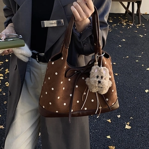 Dettaglio della borsa tote marrone vintage a pois con fiocco in pelle e ciondolo orso