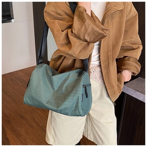 Close-up of green checkered pillow bag with adjustable black wide strap for daily commute