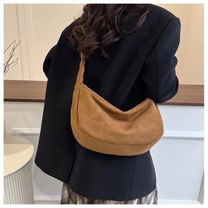 Model draagt een bruine suède hobo dumpling tas met zwarte blazer en geruite rok