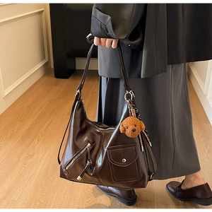 Detail view of large dark coffee faux leather tote with adjustable strap and bear pendant