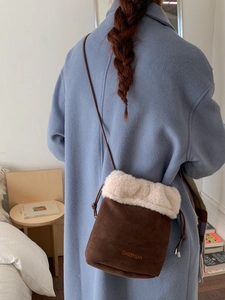 Retro suede bucket bag with plush trim and adjustable strap shown on model's shoulder