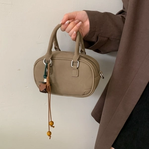 Close-up of khaki Boston bag with matte leather texture and beaded tassel detail