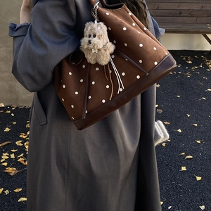 Dettaglio della borsa tote vintage marrone a pois con ciondolo a cane e cappotto autunnale