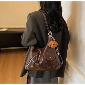 Detail view of deep brown faux leather shoulder bag with plush dog charm for daily commute