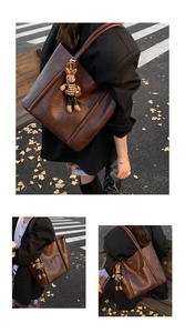 Detail view of large retro brown tote bag with cute rabbit charm on autumn street