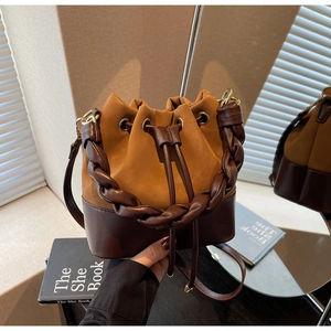 Detail of a retro drawstring bucket bag featuring a two-tone design and woven handle