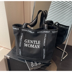 Dettaglio della borsa tote in tela nera con stampa logo bianco e manici robusti