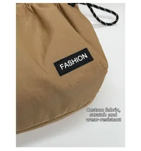 Detail of khaki drawstring crossbody bag showing durable nylon fabric and fashion label