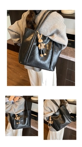 Detail of black textured leather tote bag with a cute rabbit charm and dual handles