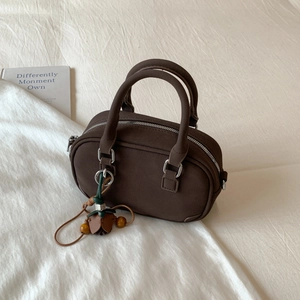 Detail of dark coffee Boston bag featuring a floral pendant on a textured suede fabric