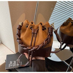 Close-up of dual-tone bucket bag featuring woven handle and drawstring closure detail