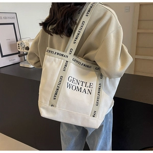 Dettaglio della borsa tote in tela di alta qualità con logo del marchio e tracolla in tessuto