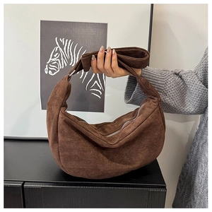 Detailopname van donkerbruine suède hobo-tas met brede schouderriem en zilveren rits