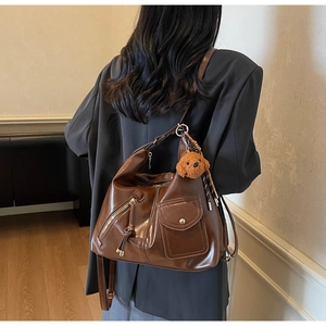 Brown leather hobo bag featuring zipper details and a cute teddy bear plush charm