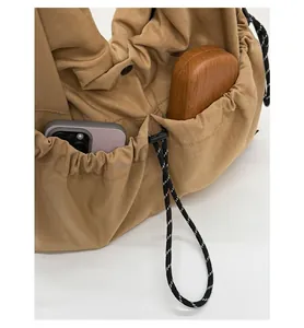 Detail showing the adjustable drawstring side pocket on a khaki casual tote bag
