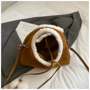 Détail du sac en daim caramel avec bordure en laine d'agneau et pompons décoratifs