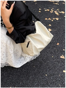 Detail of a beige plaid pillow crossbody bag on an autumn street with ginkgo leaves