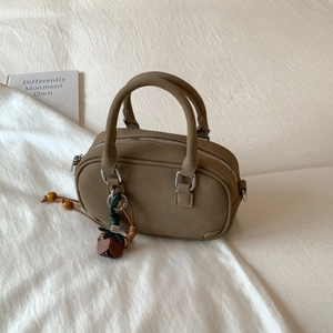 Detail of earthy mini Boston bag with matte leather texture and tulip pendant charm