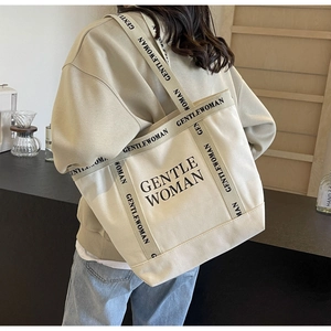 Dettaglio di una borsa tote in tela grande con scritta Gentle Woman su una modella