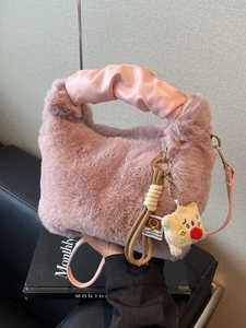 Borsa in peluche rosa con manico in pelle e ciondolo toast tenuta in mano