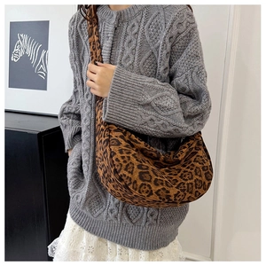 Detail van een trendy halve maan tas met luipaardprint op een model met een trui