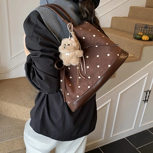 Vista dettagliata della borsa tote in pelle scamosciata a pois con ciondolo peluche