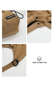 Detail view of khaki drawstring bag featuring FASHION label, snap button, and buckle