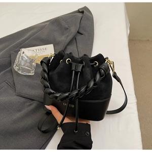 Detail of black drawstring bucket bag with leather patchwork and woven handle
