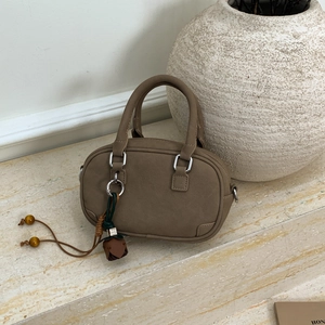 Detailed macro view of a brown suede bowling bag with rose charm and wooden beads