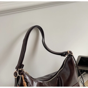 Close-up of a vintage dark brown oil-wax leather shoulder bag with silver metallic zippers