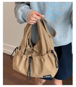 Detail view of khaki drawstring tote bag with a fashion label and adjustable rope
