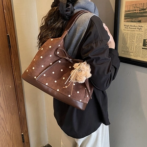 Vista dettagliata della borsa tote vintage a pois con cinturino in pelle e ciondolo a orsetto