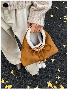 Détail d'un mini sac en daim marron avec garniture en peau de mouton et nœud déco