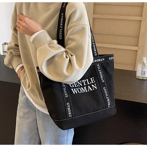 Dettaglio della grande scritta bianca GENTLE WOMAN sulla borsa tote in tela nera