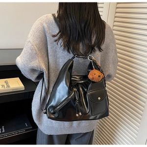 Detail of black glossy multi-functional tote bag with plush charm and silk scarf