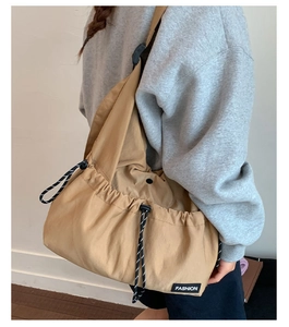 Detail of khaki crossbody bag featuring black and white drawstring and FASHION label