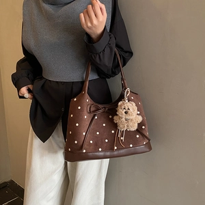 Dettaglio della borsa tote a pois con fiocco decorativo e ciondolo a forma di orsetto