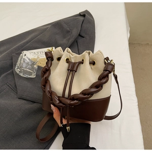 Detail of contrast bucket bag featuring woven handle and drawstring closure in daily scene