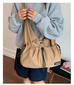 Detail of khaki nylon crossbody bag showing drawstring closure and fashion fabric label