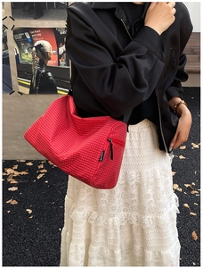 Close-up of red plaid crossbody bag with zipper detail and adjustable strap on model