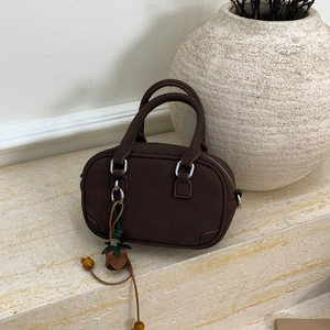Detail view of chocolate brown mini bowling bag with matte leather and green knot charm