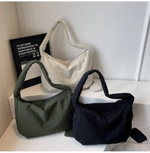 Detailansicht großer Nylon-Schultertaschen in Cremeweiß, Oliv und Schwarz mit Mini-Anhängern