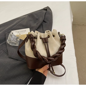 Detail of contrast bucket bag with woven handle and drawstring closure on a blazer