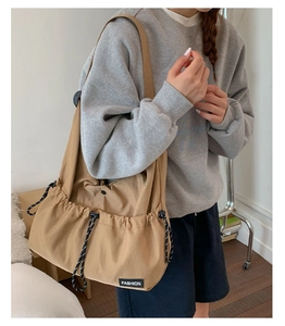 Detail view of khaki drawstring crossbody bag with large side pockets and fashion label