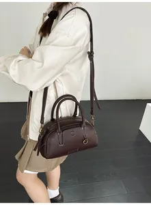 Detail of dark brown lychee leather handbag with dual handles and golden zipper hardware