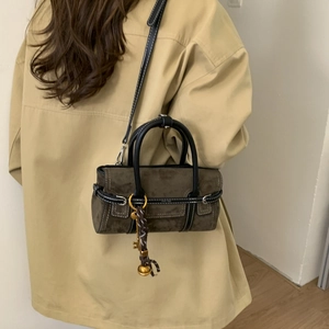 Close-up of brown suede crossbody bag with contrast stitching and golden keychain