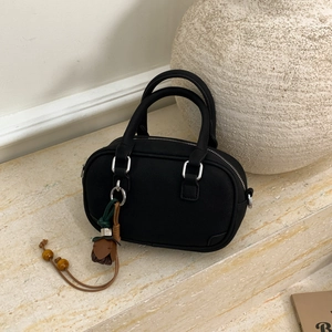 Detail of a vintage black Boston handbag with elegant tassel charm and wood bead decor