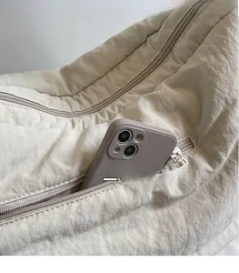 Detail der beigen gesteppten Hobo-Tasche mit Seitentasche und Smartphone-Fach