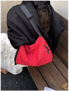 Detail of red checkered crossbody bag with adjustable strap and side pocket view