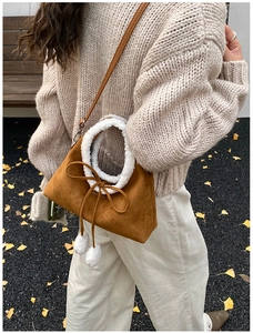 Détail du sac seau en daim marron avec bordure en fausse fourrure blanche et pompons
